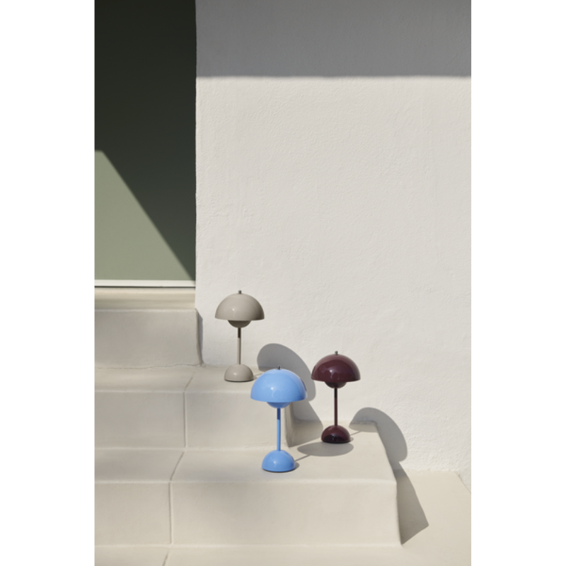 The Flowerpot VP9 Portable Table Lamp from &Tradition in multiple color styles outdoors on a set of steps.