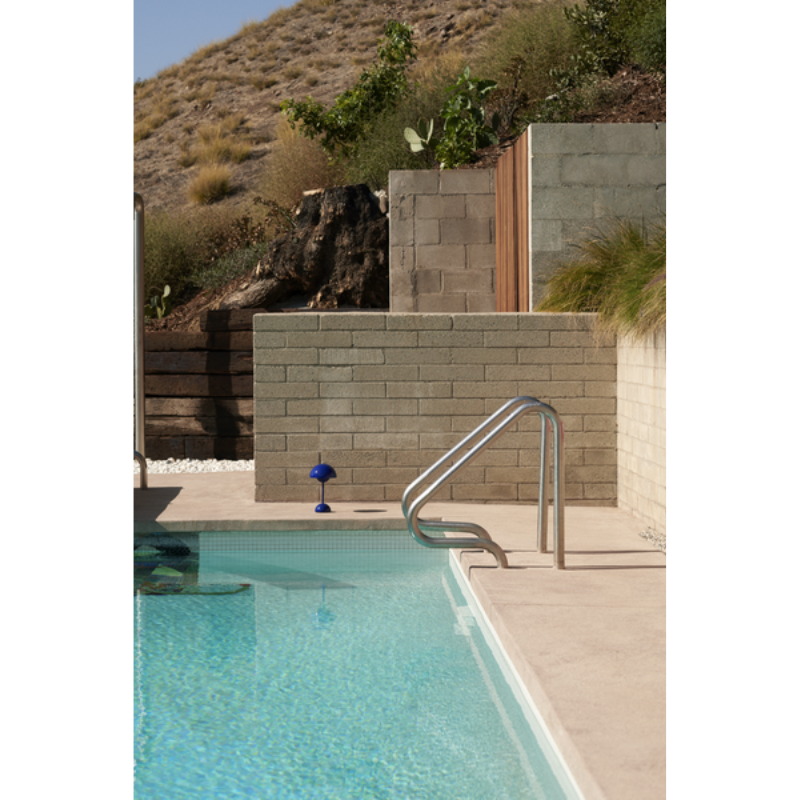 The Flowerpot VP9 Portable Table Lamp from &Tradition next to a pool.