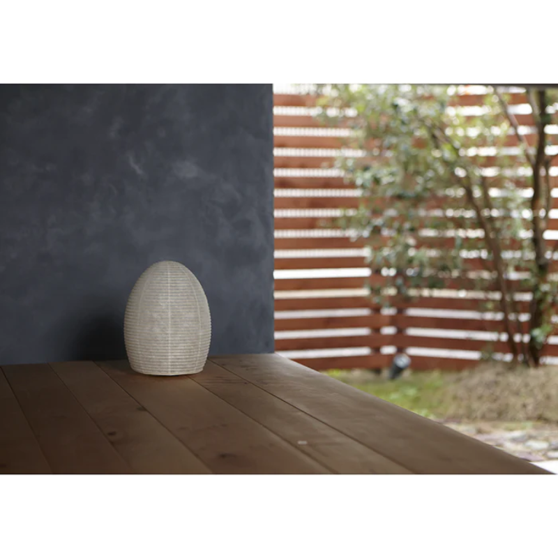 The Paper Moon 1 lamp by Asano outdoors on a porch within a garden during daytime, turned off.