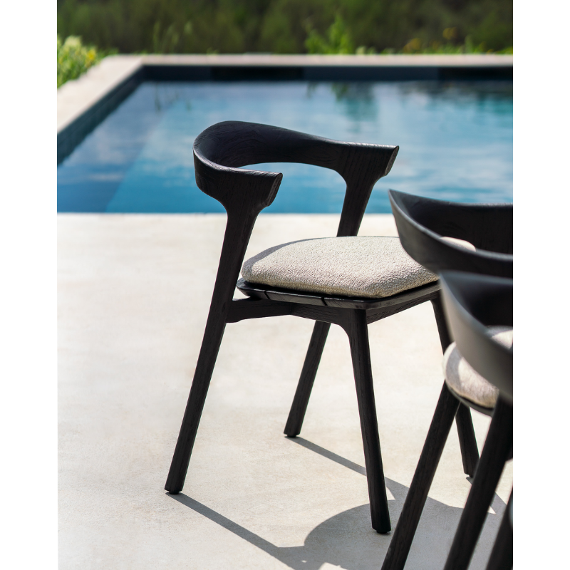 The Bok Outdoor Dining Chair from Ethnicraft in an outdoor lounge area by the pool.