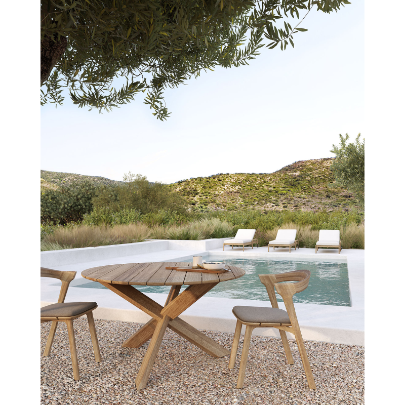 The Bok Outdoor Dining Chair from Ethnicraft to the side of a pool underneath a tree.