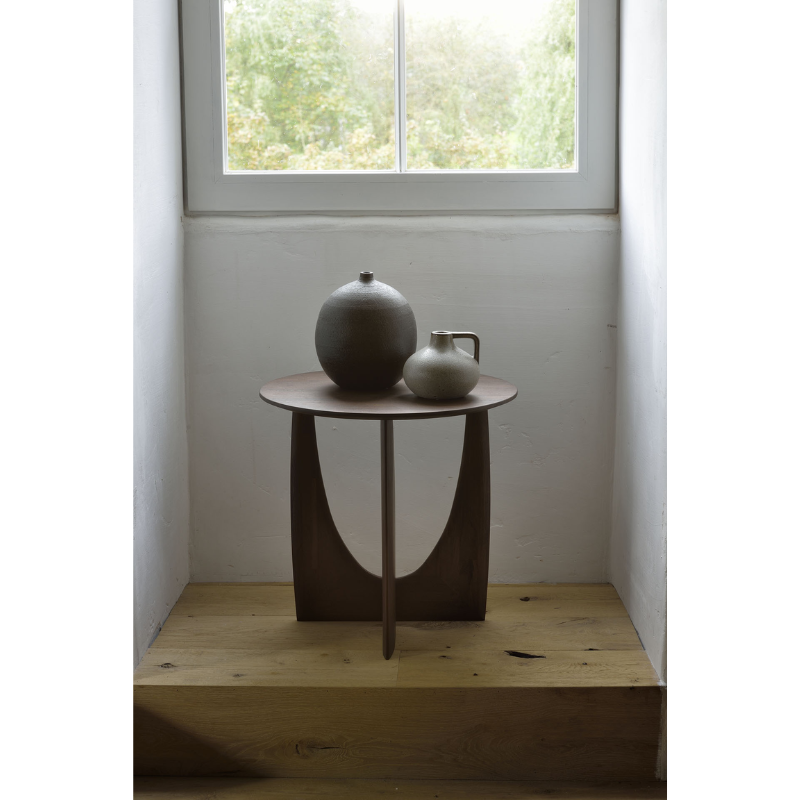 The Geometric Side Table from Ethnicraft underneath a window.