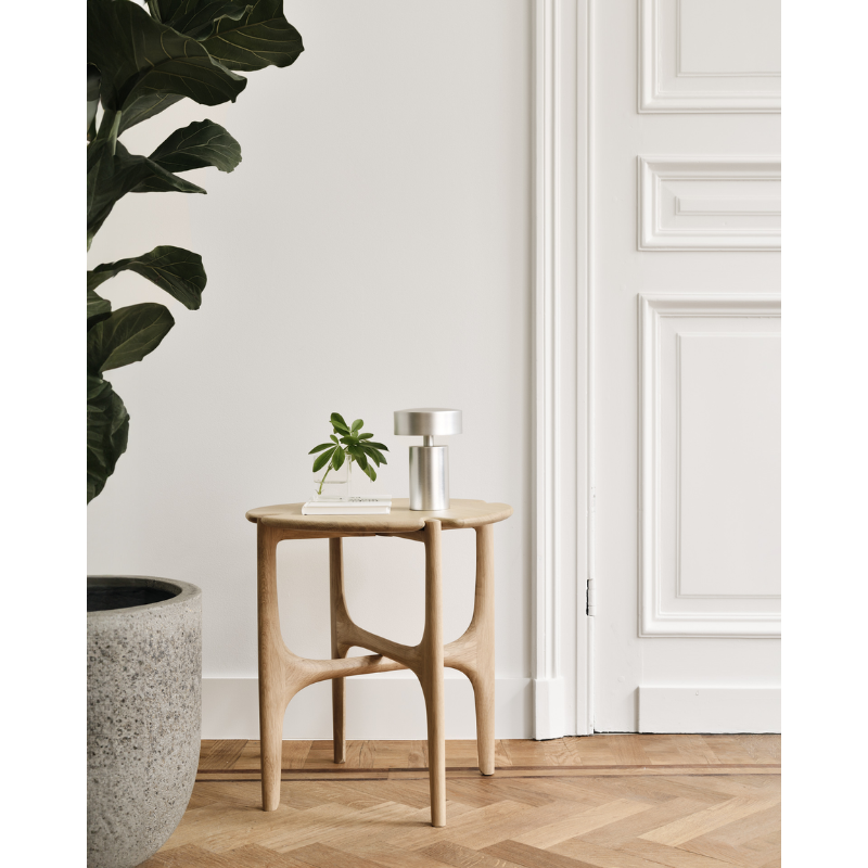 The PI Side Table from Ethnicraft next a door in an entryway.