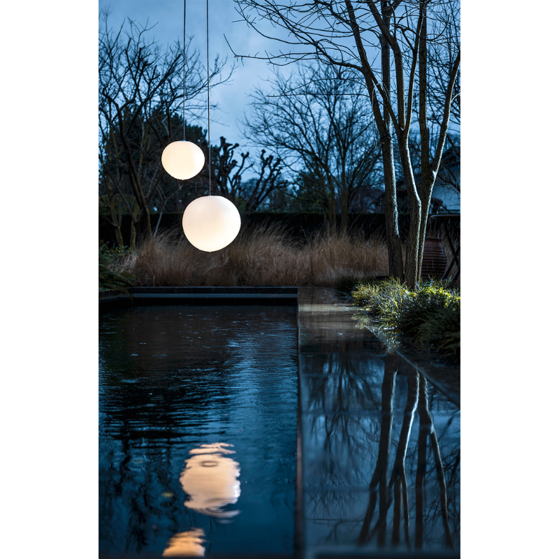 The Gregg Outdoor Pendant from Foscarini in a backyard.