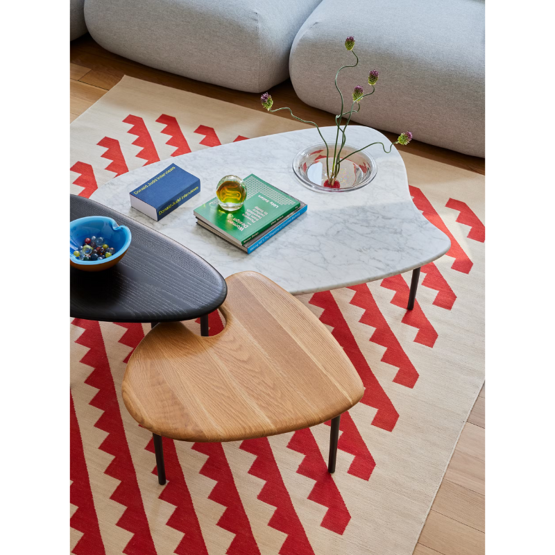 The low carrara marble with bowl, mid white oak and high black Cyclade Table from Herman Miller in a living room.