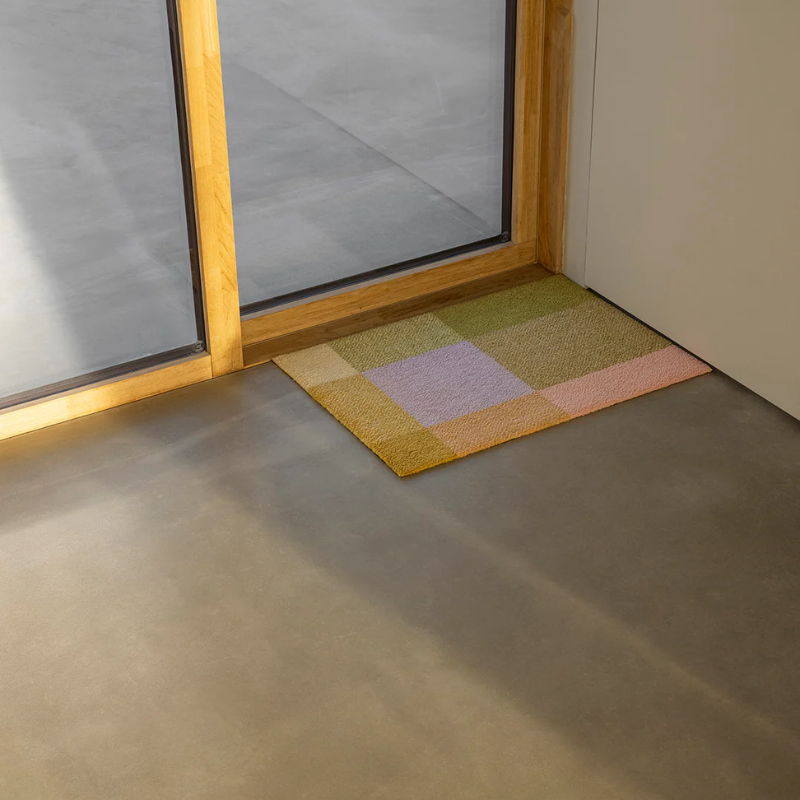 The Mix Teklan Entry Mat from Heymat in the small size beside an entryway.
