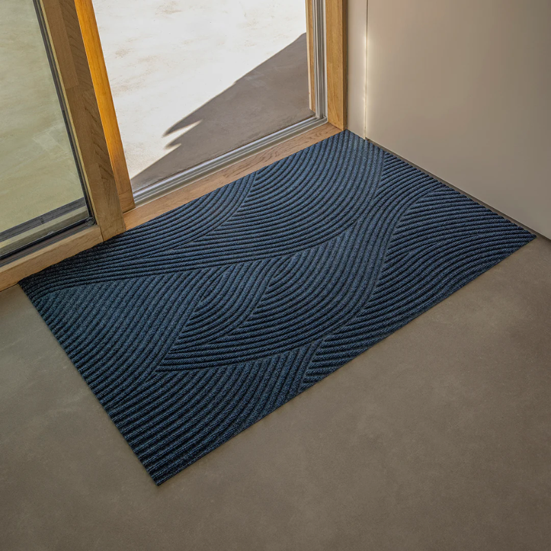 The Sjø Doormat from Heymat in the large size beside a doorway.
