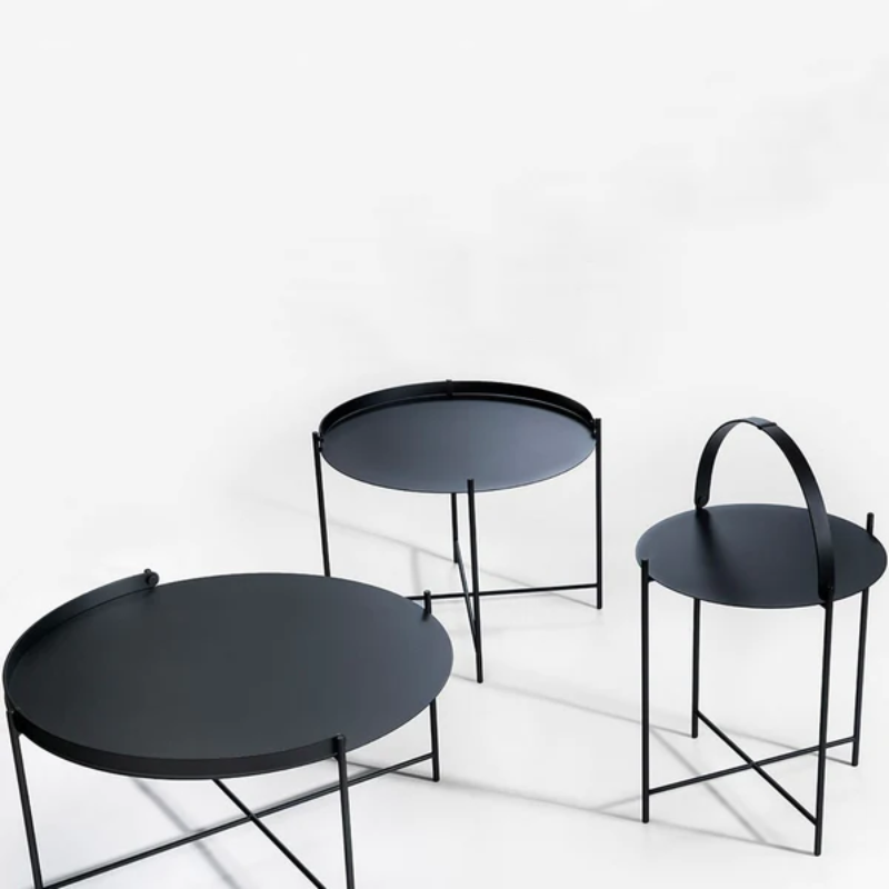 The EDGE tray table is a versatile piece of furniture that can be used both indoors and outdoors. It is made of powder-coated metal and comes in three different sizes. The half-ring shaped handle makes it easy to move the table between the living room and the garden, and when laid down it functions as a table edge making sure everything stays in place.