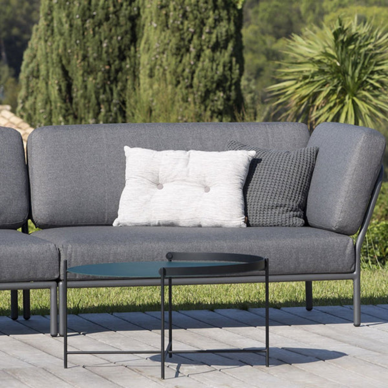 The EDGE tray table is a versatile piece of furniture that can be used both indoors and outdoors. It is made of powder-coated metal and comes in three different sizes. The half-ring shaped handle makes it easy to move the table between the living room and the garden, and when laid down it functions as a table edge making sure everything stays in place.