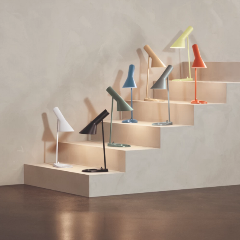 The AJ Mini Table Lamp from Louis Poulsen in a photograph highlighting the light colors within the collection. all-groups