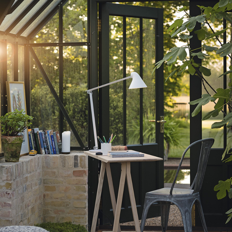 The NJP Table from Louis Poulsen in a garden lifestyle photograph.