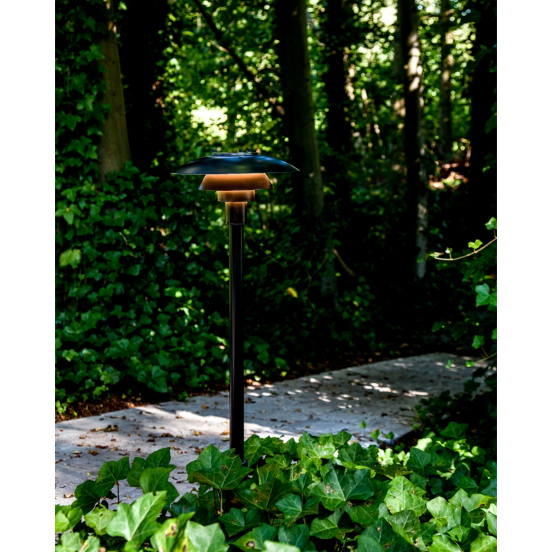The PH 3-2½ Bollard from Louis Poulsen in a garden.