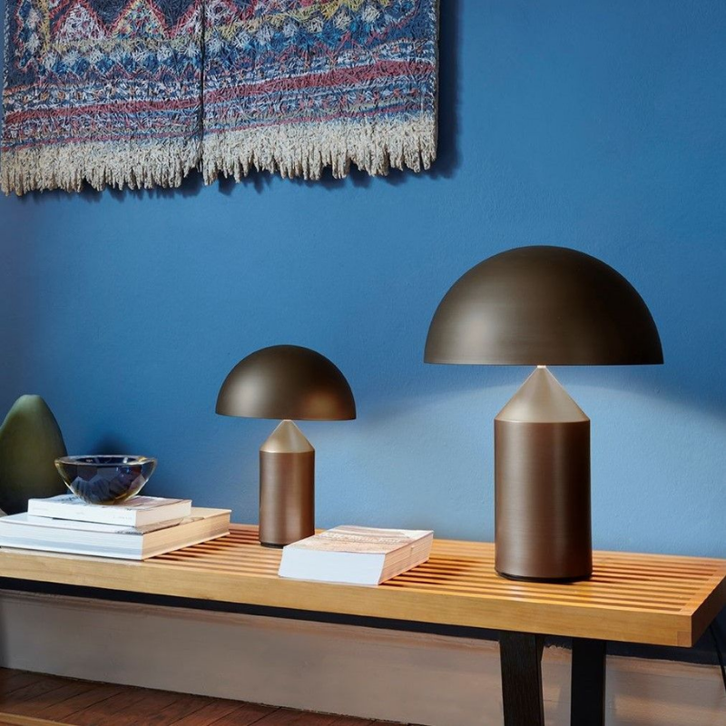 This is the Atollo Satin Bronze Table Lamp from Oluce on a small table within a den.
