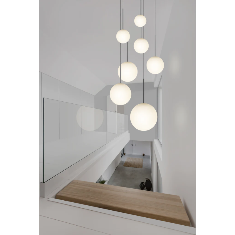 The Bola Sphere from Pablo Designs in a hallway above a staircase in various sizes.