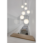 The Bola Sphere from Pablo Designs in a hallway above a staircase in various sizes.