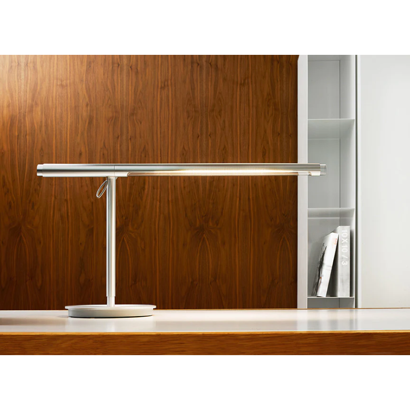 The Brazo Table light from Pablo Designs in silver being used in an office.