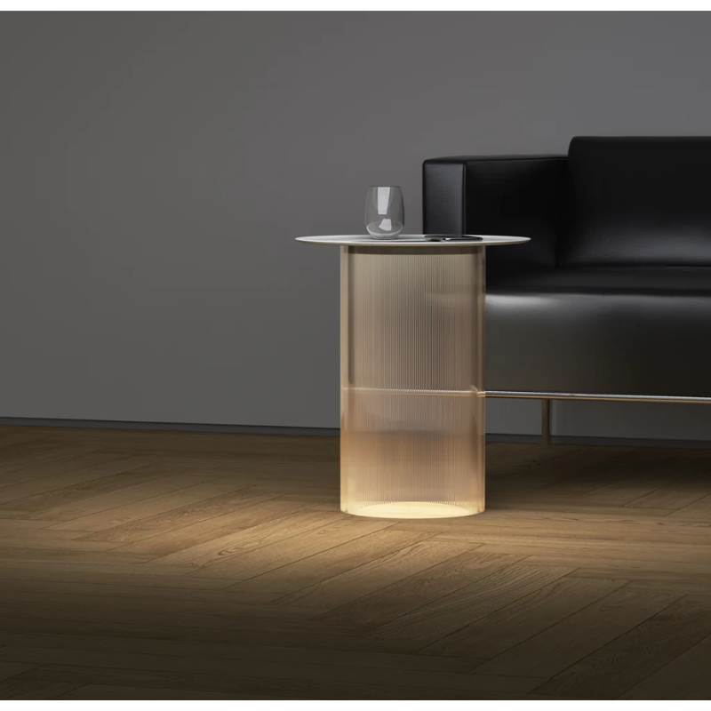 The Carousel Floor from Pablo Designs in a lounge area next to a sofa with a glass on top.