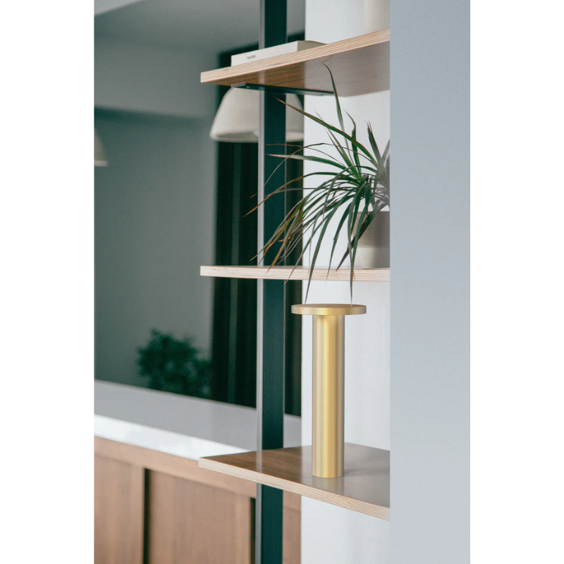 The Luci Table from Pablo Designs in a lounge space on a bookshelf.