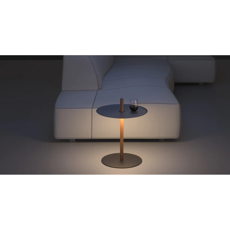 The Nivél Pedestal from Pablo Designs next to a sofa in a living room.