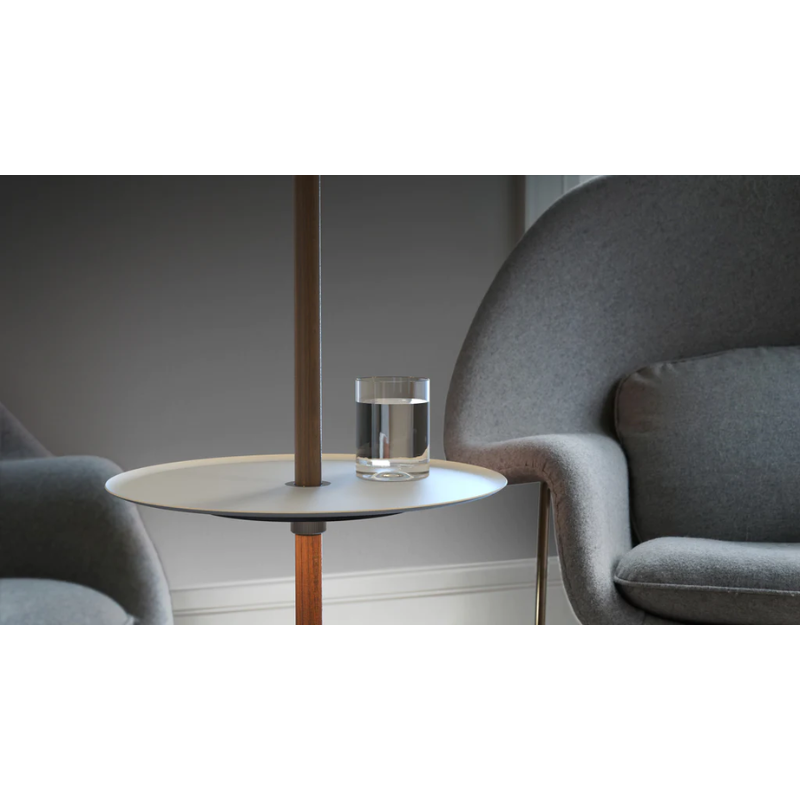 The Nivél Pedestal from Pablo Designs next to two lounge chairs, holding a glass of water.