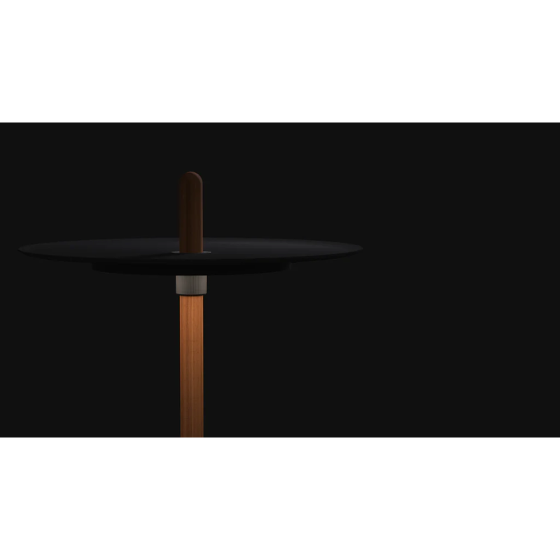 The Nivél Pedestal from Pablo Designs turned on within a dark room.