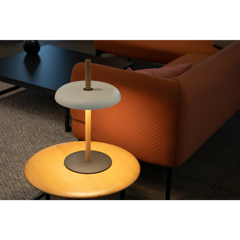 The Nivél Table from Pablo Designs next to a sofa in a living room.