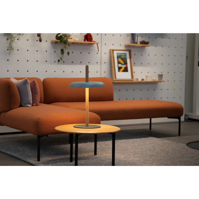 The Nivél Table from Pablo Designs next to a couch in a lounge space.