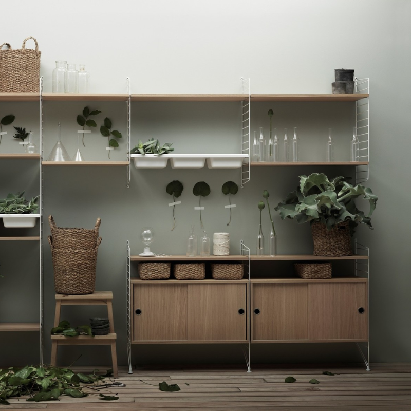 The Cabinet with Sliding Doors from String Furniture being used for decor and storage.