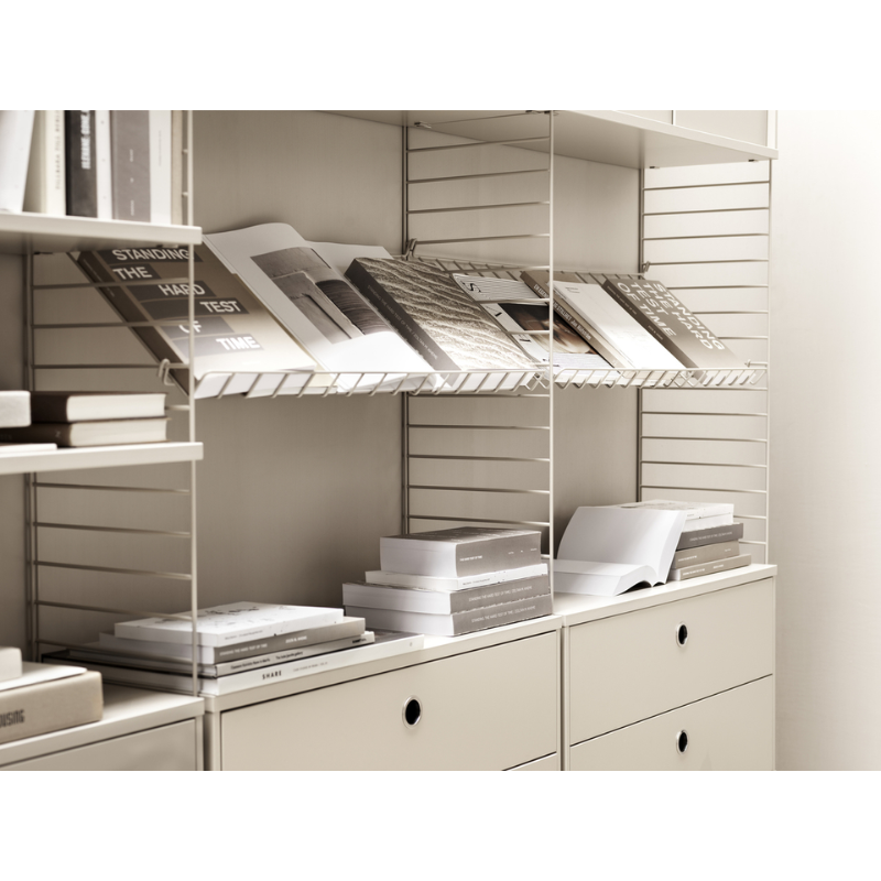 The Metal Magazine Shelves from String Furniture in a closet holding books.
