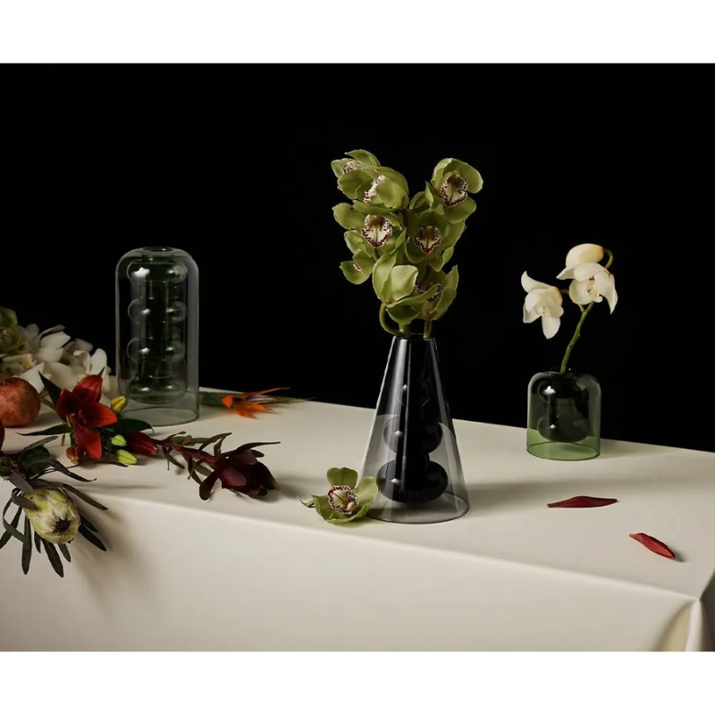 The Bump Vase Cone Black from Tom Dixon being used on a covered tabletop with flowers.
