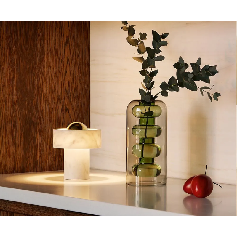 A Bump Vase Tall in Green by Tom Dixon in a living room.