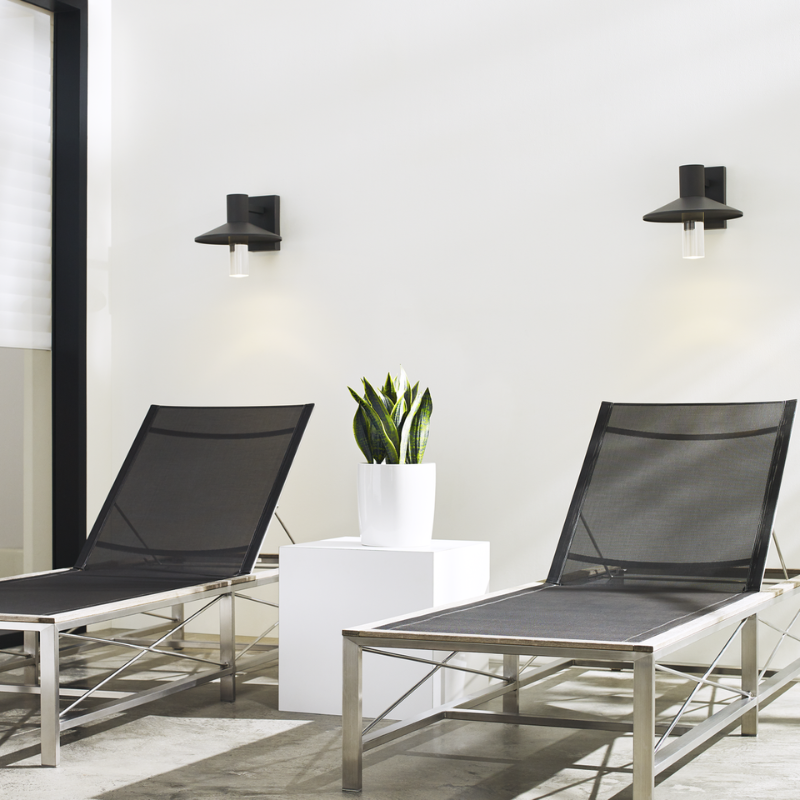 The Ash Cylinder Outdoor Wall Sconce from Visual Comfort and Co. in an outdoor lounge lifestyle photograph.