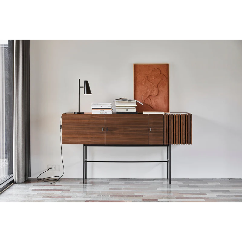 The Array series is inspired by the wooden slate cladding found in modern architecture. With its geometric shape and horizontal slats, it creates a strong visual effect from catching both light and shadow in the depth of the slats. The sleek legs lift the sideboards from the ground creating an elegant contrast between the solid wooden cabinet on top and the thin metal construction underneath. Soft closing doors make the cabinet both functional and delicate.