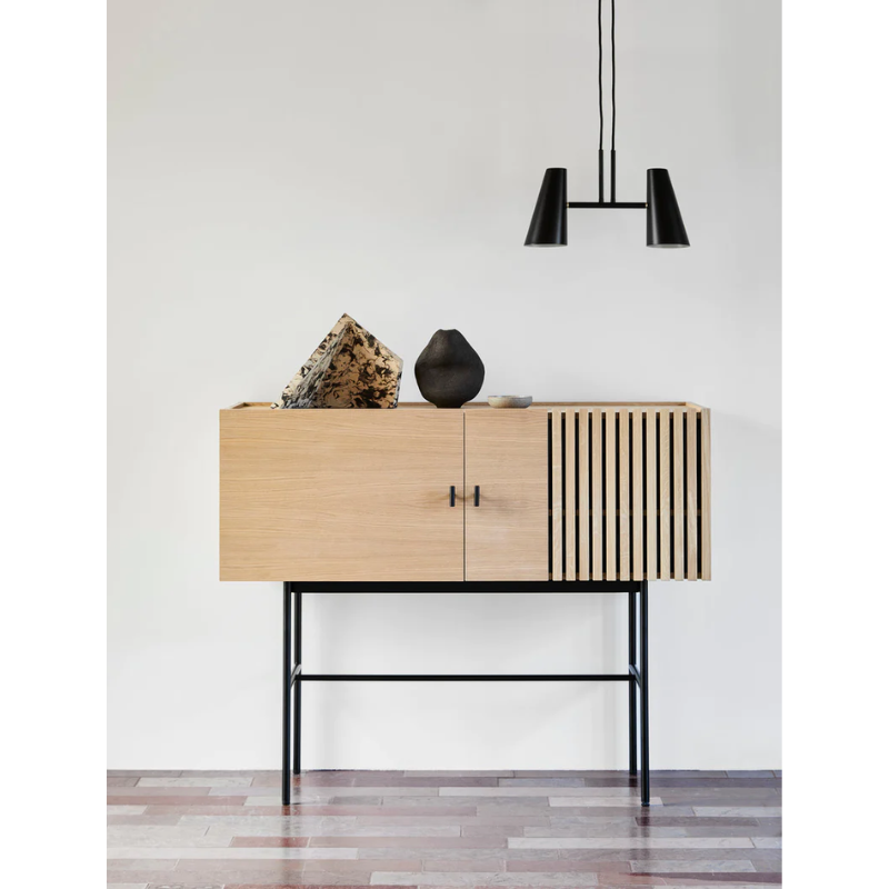 The small Array Sideboard from Woud in white pigmented oak being used for decor and storage.