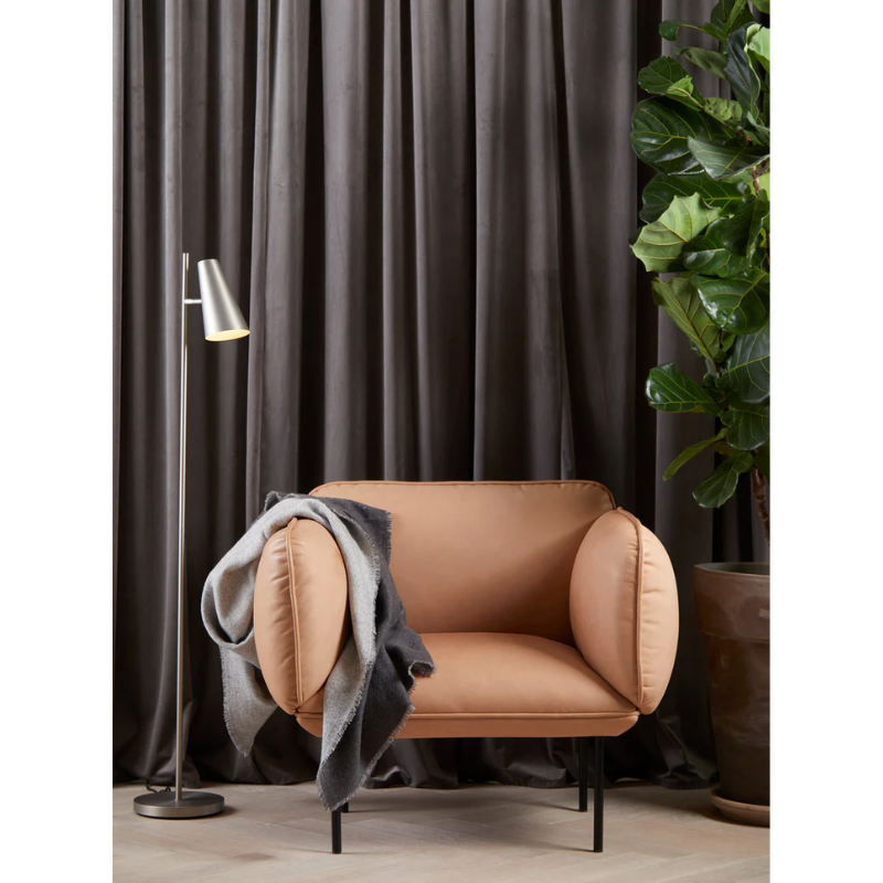 The Double Throw from Woud on the arm of a chair in a lounge area.