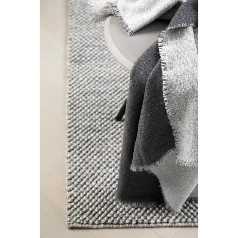 The Double Throw from Woud on top of a side table with a Woud rug.