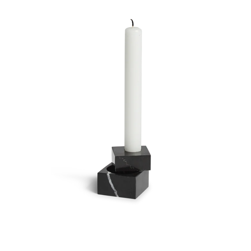 The solid marble Jeu De Dés 1 Candle Holder from Woud with a taper candle in black.