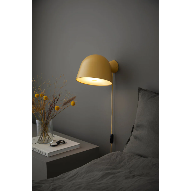 The Kuppi Wall Lamp 2.0 from Woud in a bedroom.
