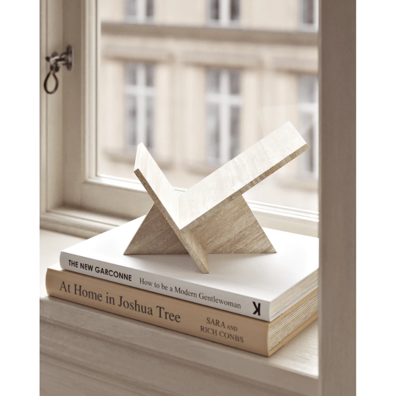 The Mountain Paperweight from Woud on top of a stack of books within a living room.