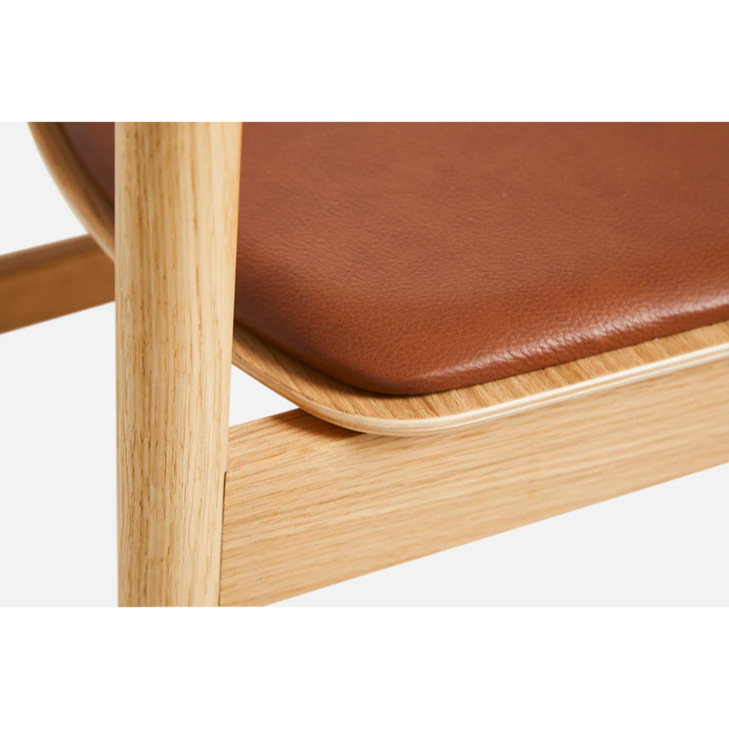 A close up on the Pause Dining Chair 2.0 from Woud in Oiled Oak with Leather.
