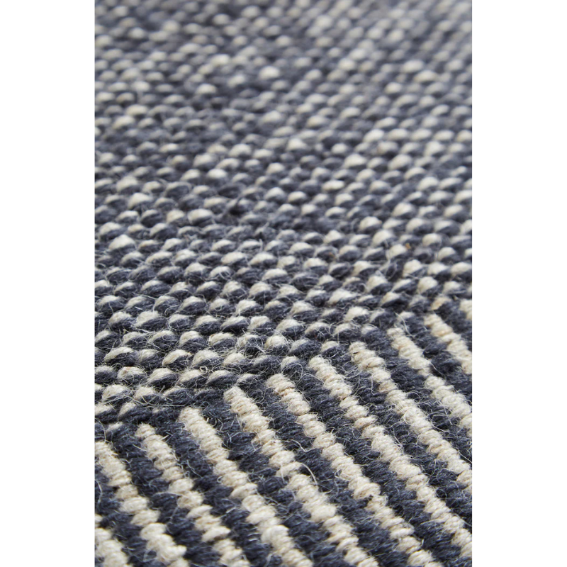 A close up on the grey fabric of the Rombo Rug.
