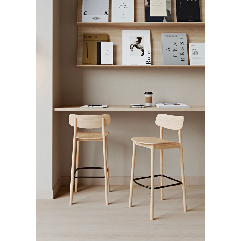 The Soma Bar Stool from Woud next to a counter with coffee on top and books above.