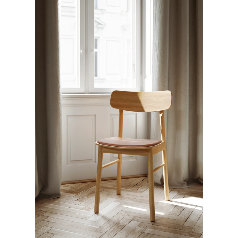 The Soma Dining Chair from Woud in Oiled Oak with Leather in a lifestyle shot.