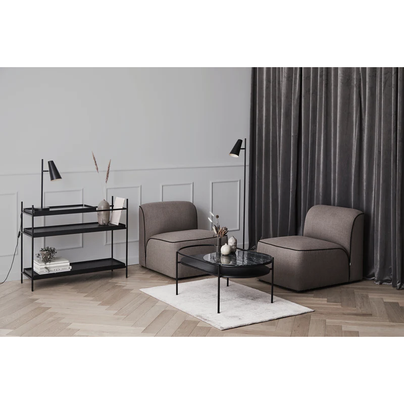 The low oak Tray Shelf in a living room next to a seat.