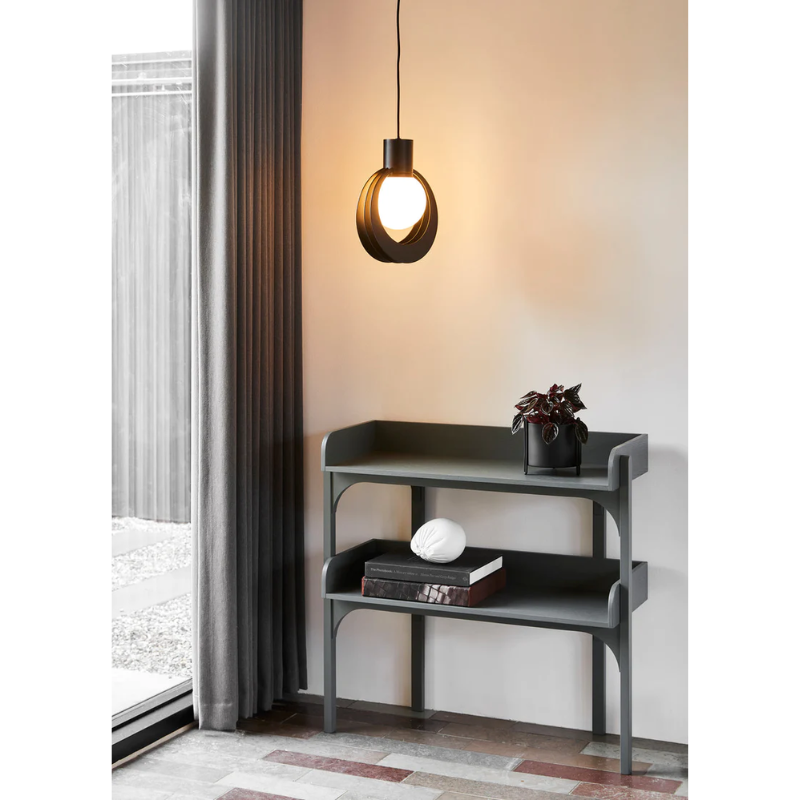 The Utility Shelf from Woud in Dusty Green nestled next to a window in a living room.