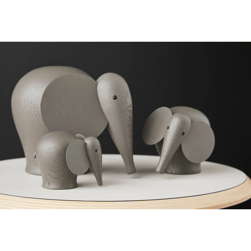 The solid oak Nunu Elephant from Woud painted taupe in a lifestyle photograph on top of a table.