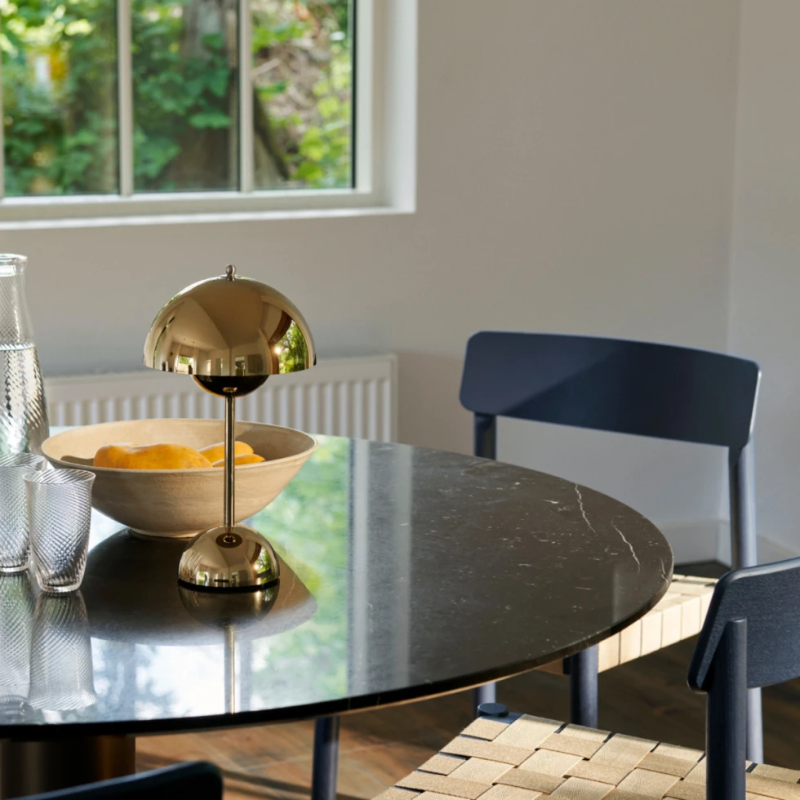 &Tradition VP9 Flowerpot Portable Table Lamp in brass plated on a dining room table.