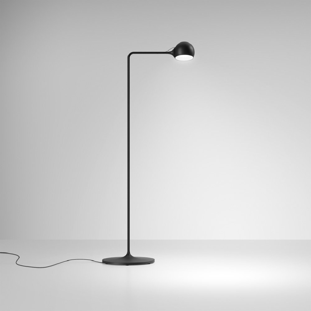 The anthracite gray Ixa Reading Floor Lamp from Artemide in a living room.