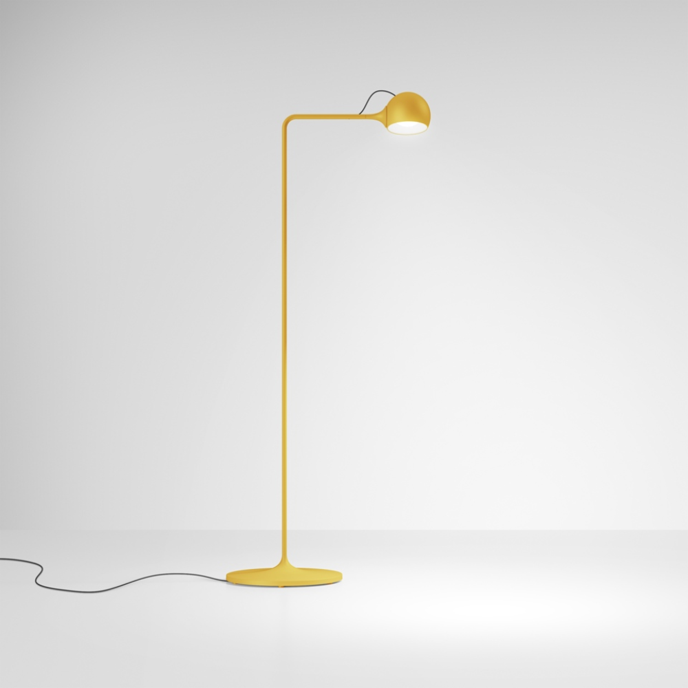 The yellow Ixa Reading Floor Lamp from Artemide in a family room.