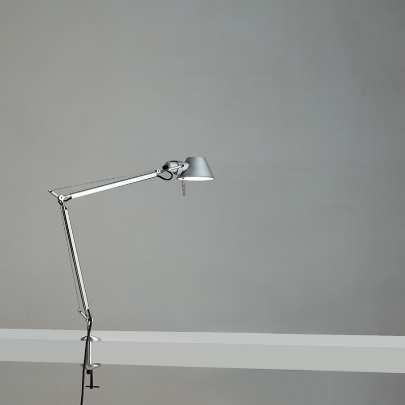 The Tolomeo Midi Table Lamp from Artemide in aluminum with the table clamp in a studio.